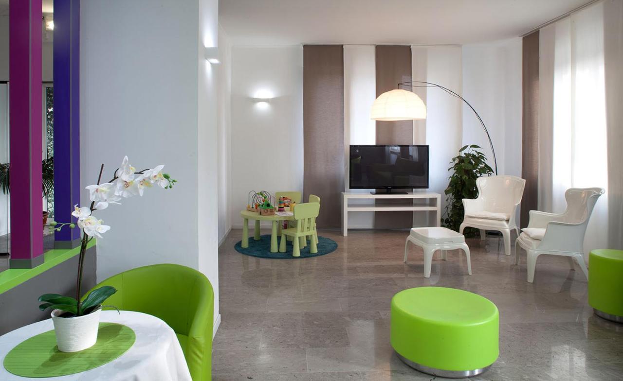 een woonkamer met groene stoelen en een televisie bij Hotel Milano Palmanova in Milaan