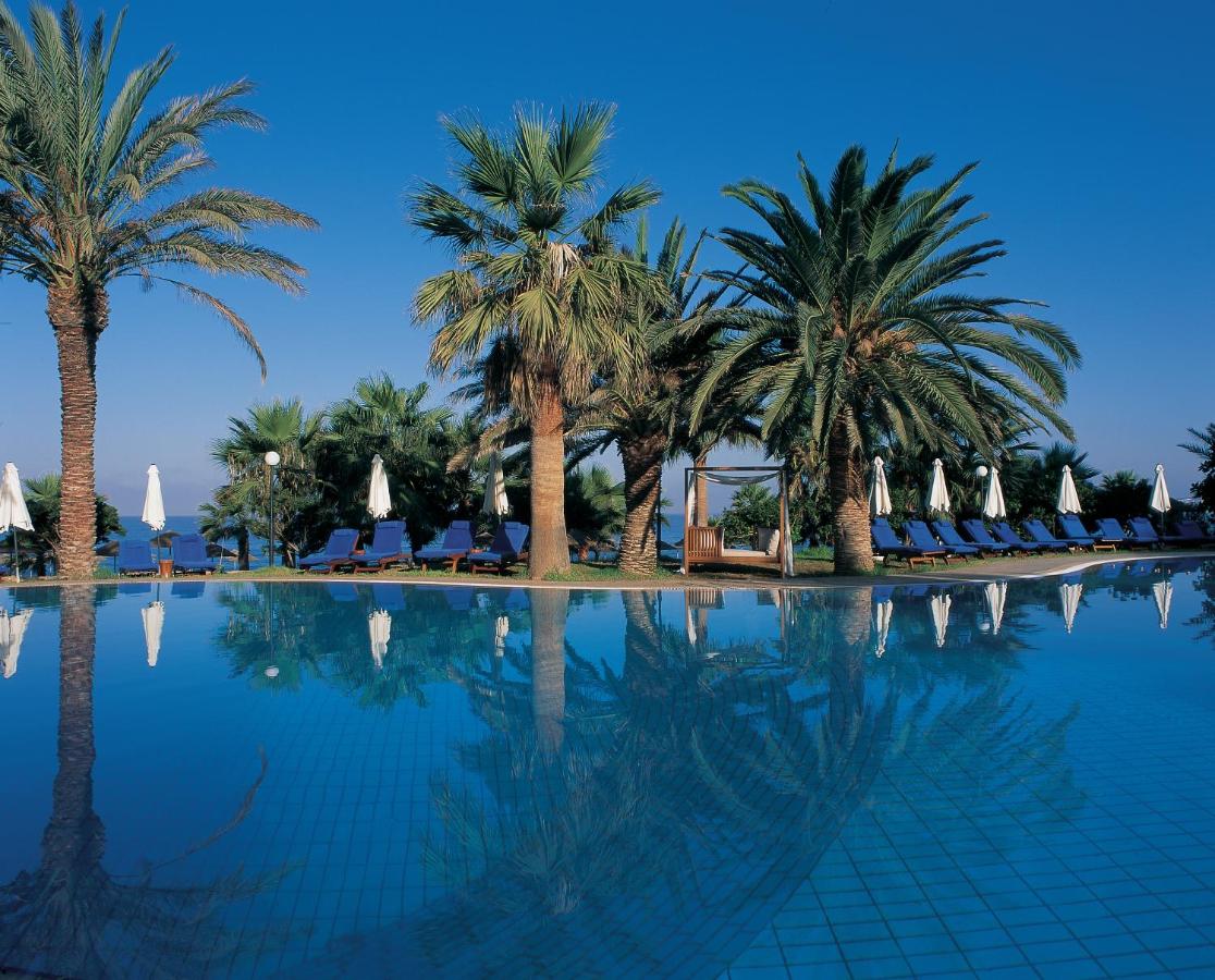 een zwembad met palmbomen en ligstoelen bij Azia Resort & Spa in Paphos City
