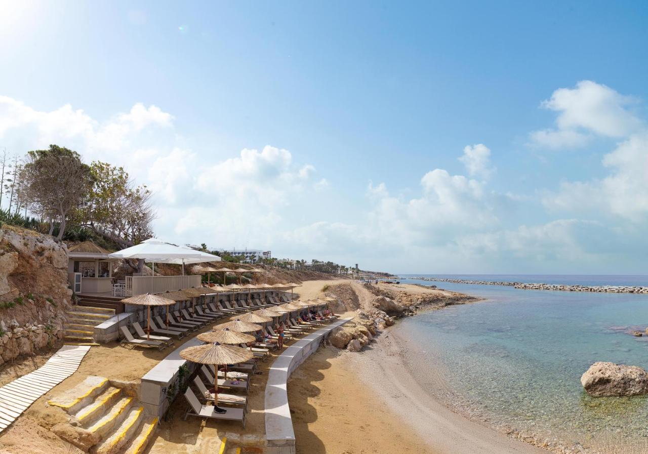 een strand met stoelen en parasols en de oceaan bij Leonardo Laura Beach & Splash Resort in Paphos City