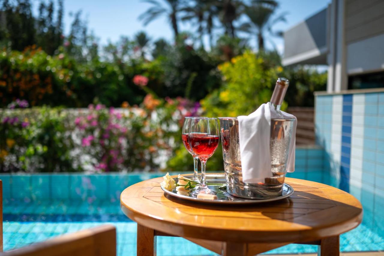 een glas wijn op een tafel naast een zwembad bij Constantinou Bros Asimina Suites Hotel in Paphos City