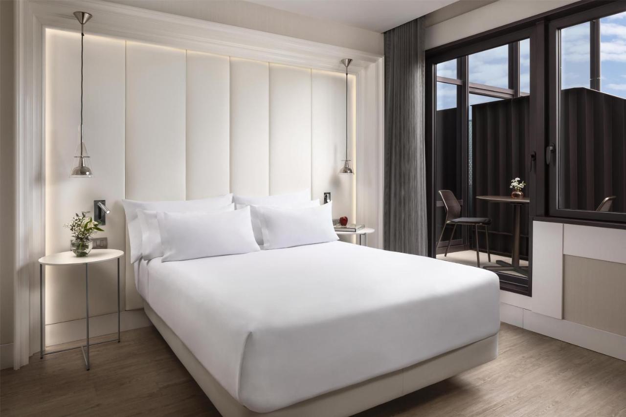 een slaapkamer met een groot wit bed en een balkon bij NH Collection Barcelona Gran Hotel Calderon in Barcelona