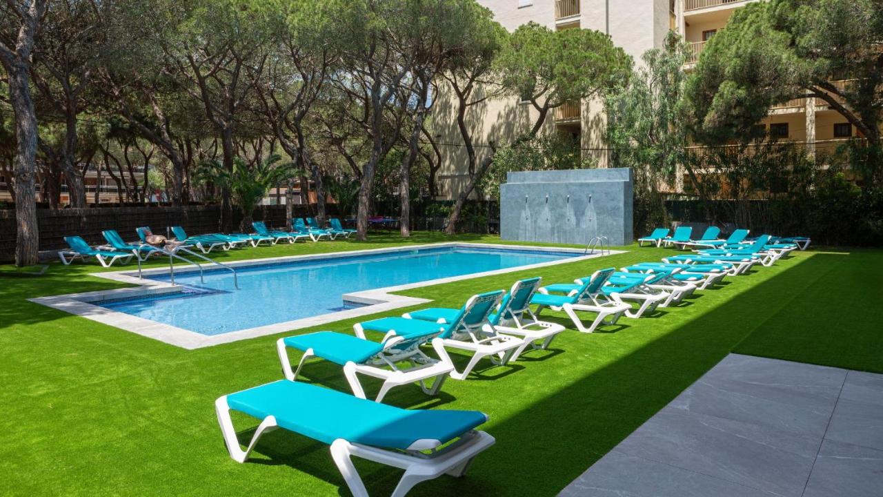 een zwembad met blauw-witte ligstoelen ernaast bij Medplaya Hotel Monterrey in Platja  d'Aro