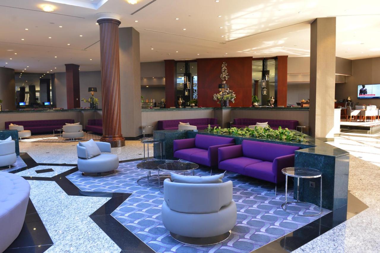 een hotellobby met paarse banken en tafels bij Grand Cevahir Hotel Convention Center in Istanbul