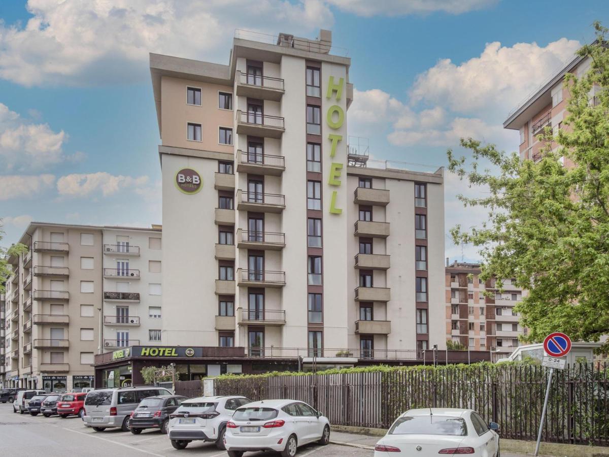 een groot wit gebouw met auto's geparkeerd op een parkeerplaats bij B&B Hotel Firenze Novoli in Florence