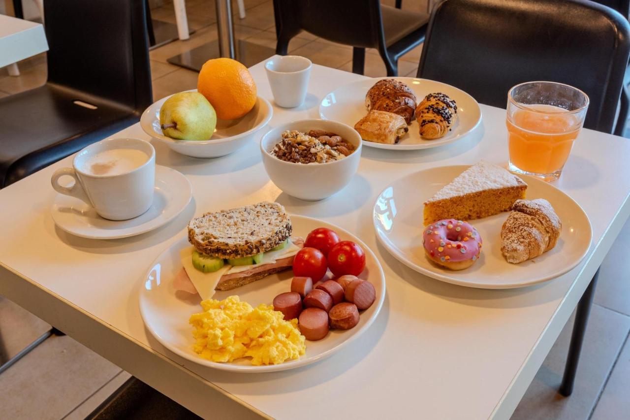 een tafel met borden vol ontbijtgerechten en drankjes bij B&B Hotel Firenze Novoli in Florence