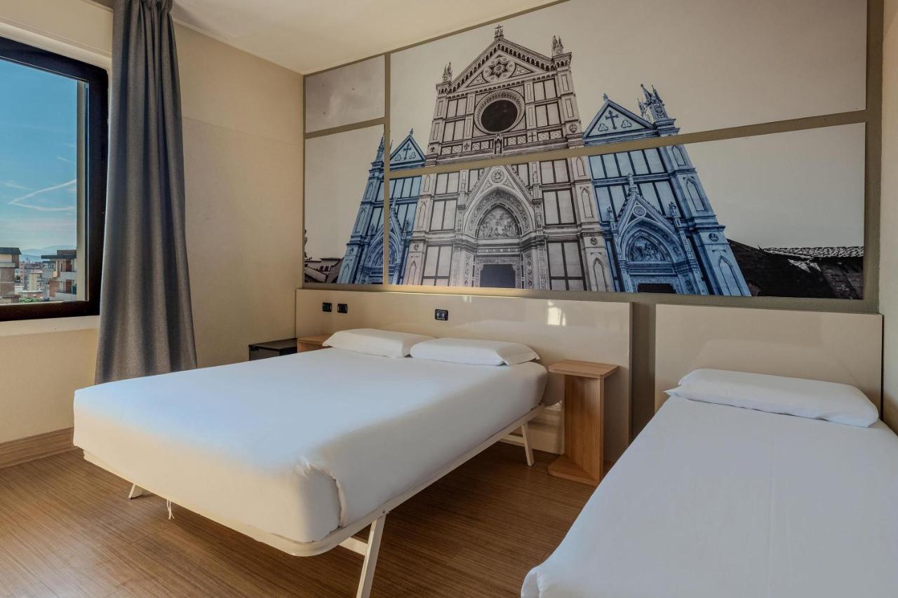 twee bedden in een kamer met een afbeelding van een kerk bij B&B Hotel Firenze Novoli in Florence