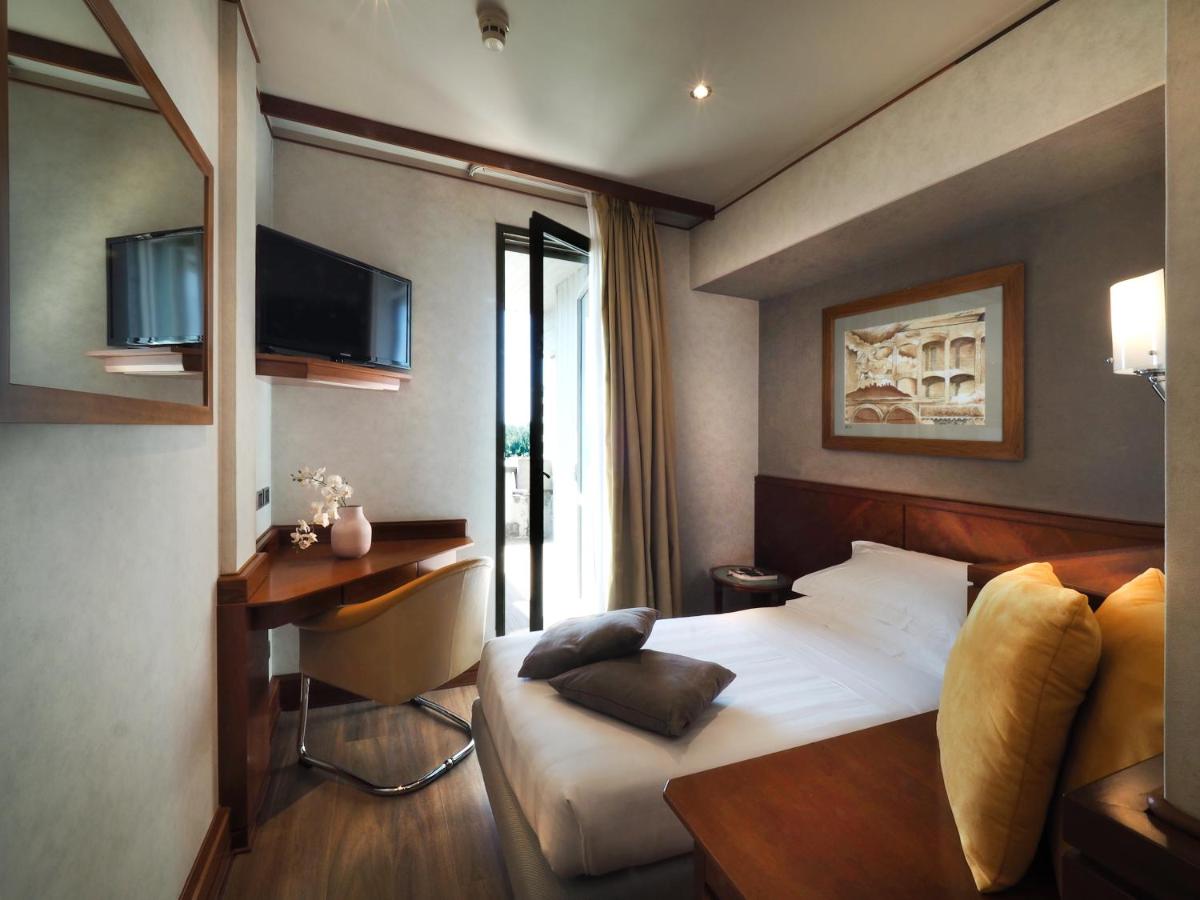 een slaapkamer met een bed, een bureau en een televisie bij Perugia Park Hotel in Perugia