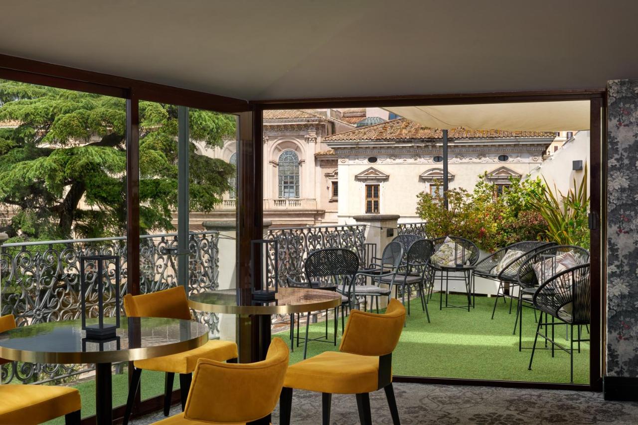 een balkon met tafels en stoelen en uitzicht op een gebouw bij Hotel Barberini in Rome
