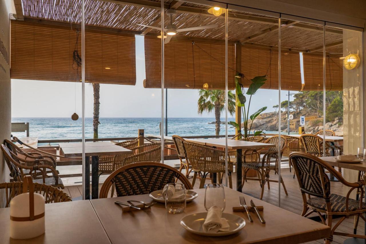een restaurant met tafels en stoelen en uitzicht op de oceaan bij Hotel Reimar in Sant Antoni de Calonge