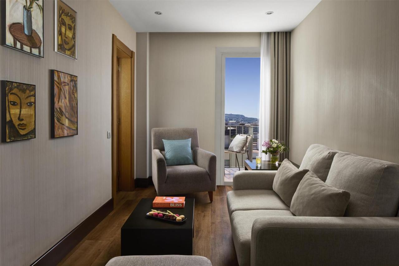 een woonkamer met een bank en een stoel bij NH Barcelona Stadium in Barcelona