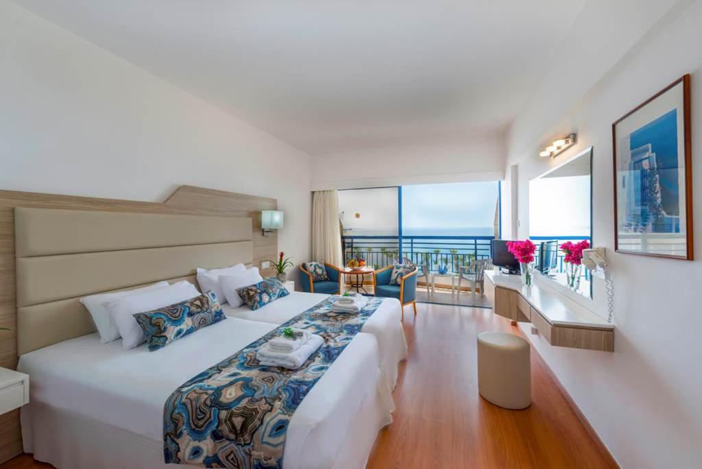 een slaapkamer met een groot bed en uitzicht op de oceaan bij Ascos Coral Beach Hotel in Coral Bay