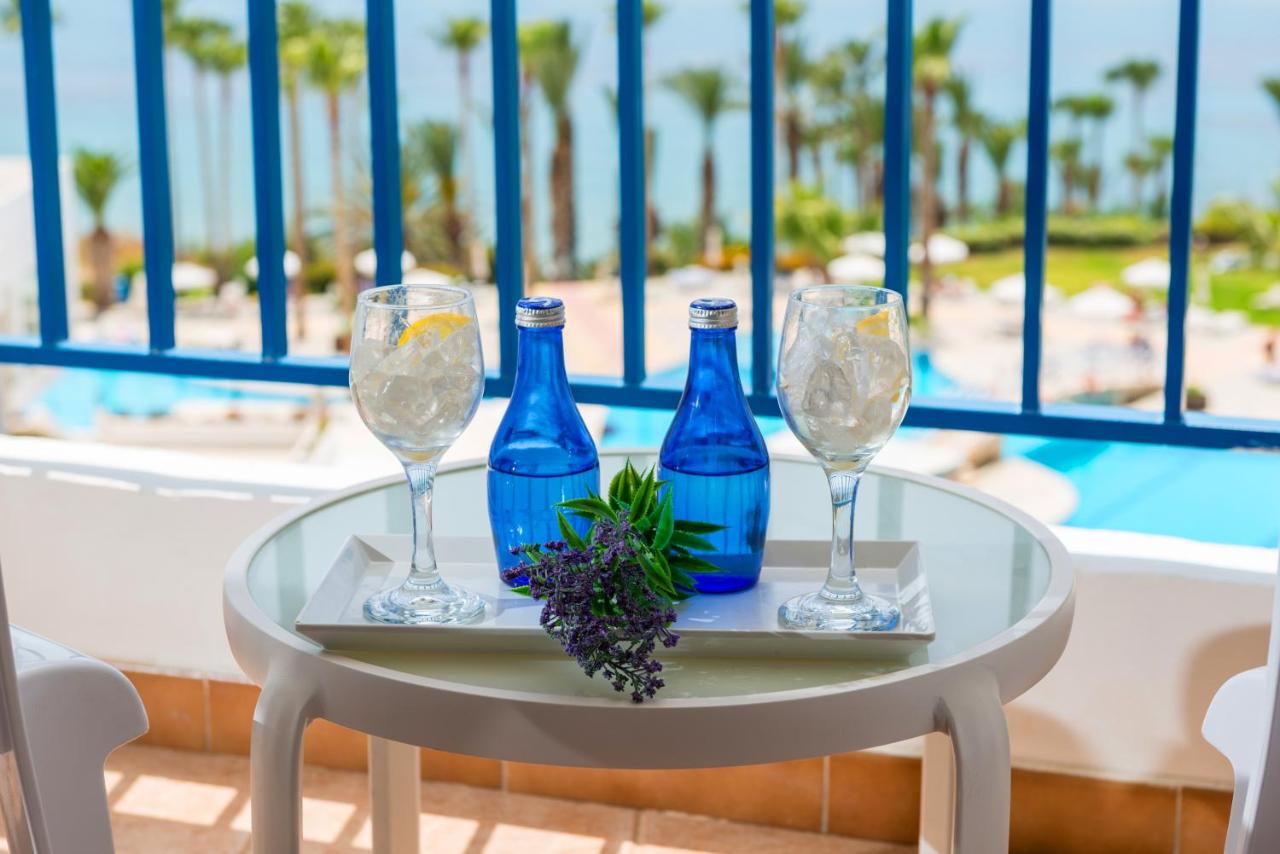 een tafel met drie blauwe flessen en glazen erop bij Ascos Coral Beach Hotel in Coral Bay