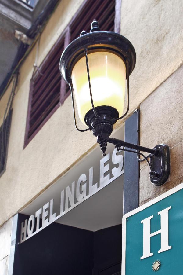 een straatlantaarn aan de zijkant van een gebouw met een bord bij Hotel Inglés in Barcelona