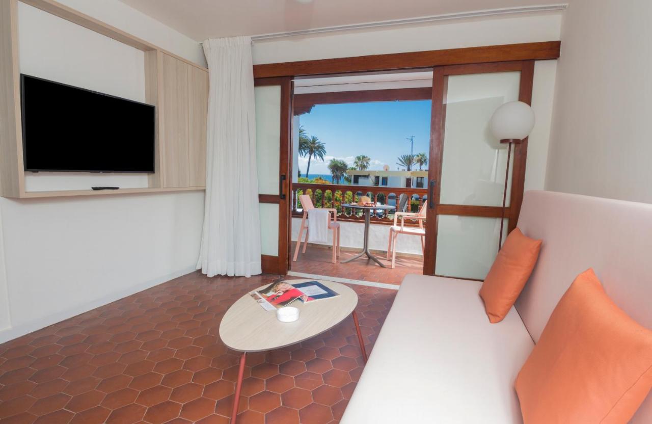 een woonkamer met een bank en een tafel bij Alsol Las Orquídeas in Playa del Inglés +48 foto's