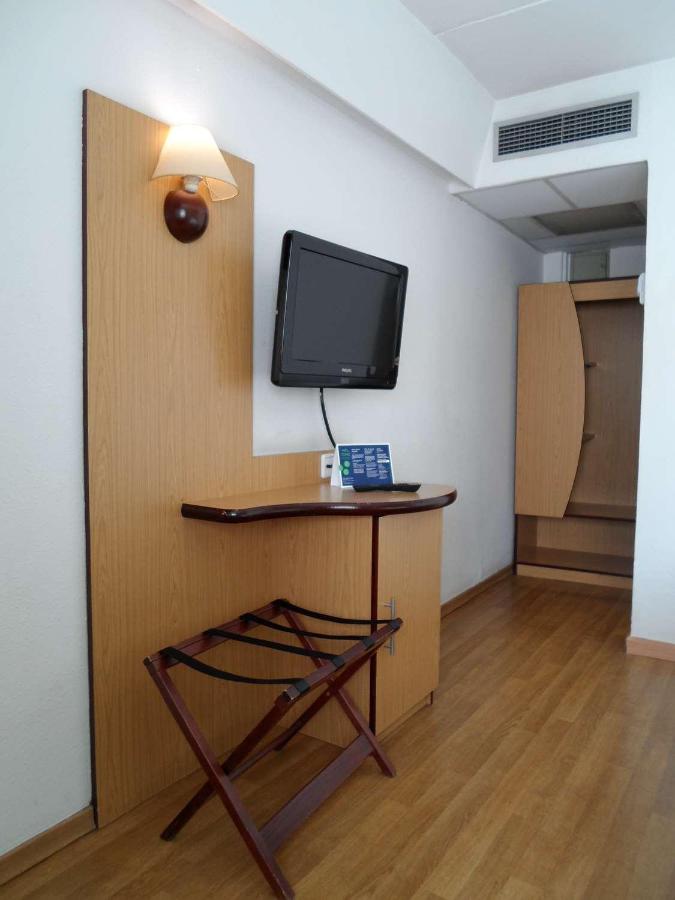 een kamer met een bureau met een televisie aan de muur bij Travelodge Barcelona del Vallés in Barbera del Valles