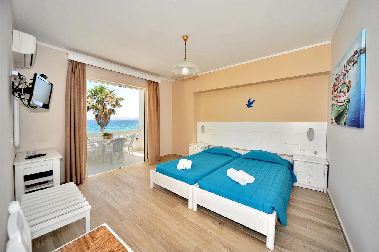 een slaapkamer met een bed en uitzicht op de oceaan bij Byron Apartments in Tigaki