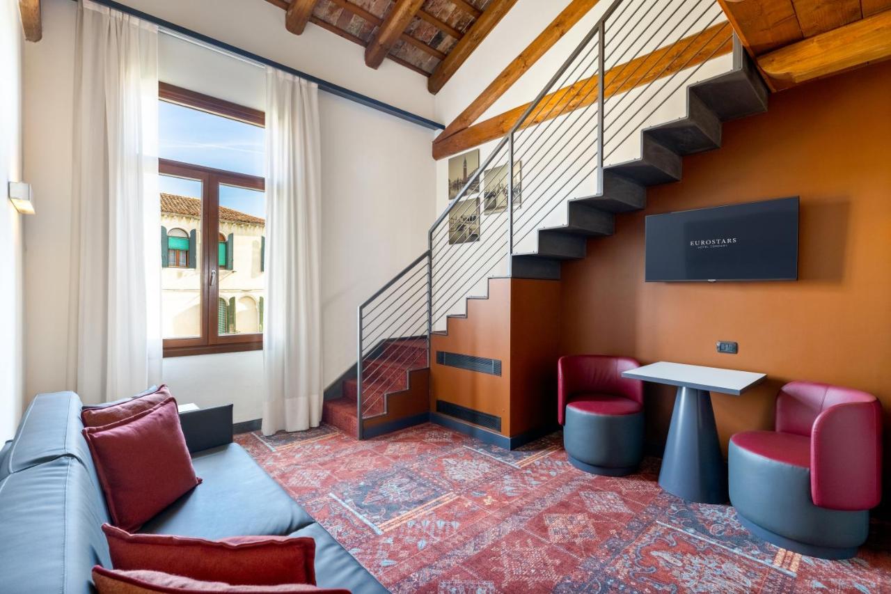 een kamer met een bank, een tafel en een trap bij Eurostars Cannaregio in Venetië