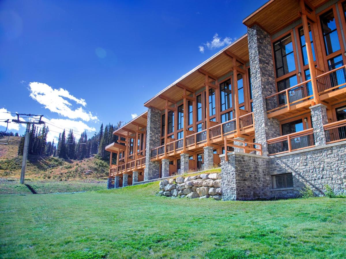 een groot houten gebouw met een grasveld ervoor bij Sunshine Mountain Lodge in Banff