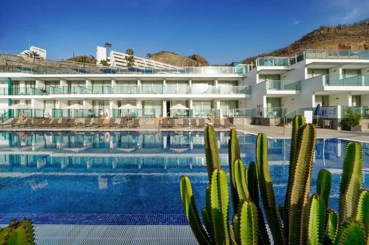 een hotel met een zwembad en cactussen bij Morasol Suites in Puerto Rico de Gran Canaria