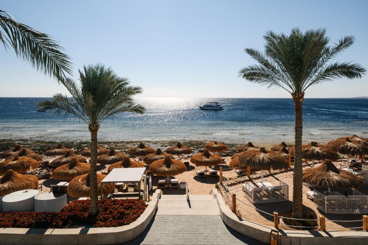een strand met palmbomen en een boot in het water bij Sunrise Remal Beach Resort in Sharm El Sheikh