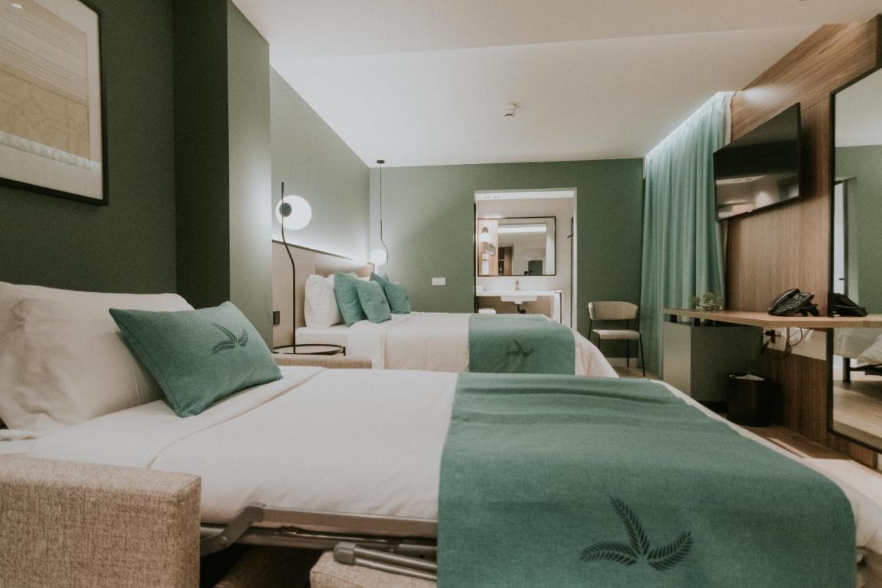 Twee bedden in een hotelkamer met groene muren. bij Catalina Plaza Hotel Sostenible in Las Palmas de Gran Canaria