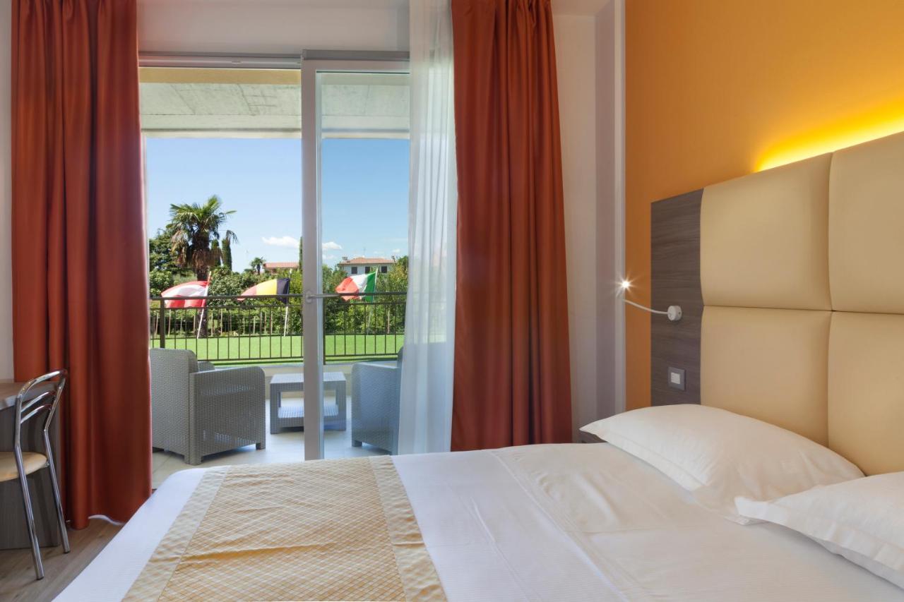 een slaapkamer met een bed en uitzicht op een balkon bij Hotel Bella Lazise in Lazise