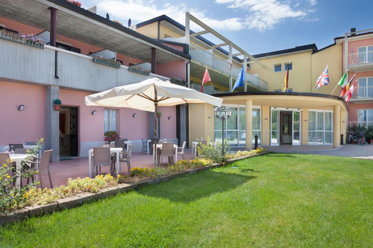 een terras met stoelen en een parasol voor een gebouw bij Hotel Bella Lazise in Lazise