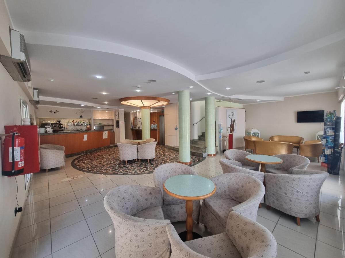 een lobby met tafels en stoelen en een keuken bij Hotel Marina in Riccione