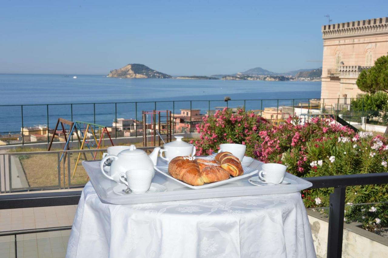 een tafel met een schaal croissants en kopjes op een balkon bij Miramare Residence in Pozzuoli