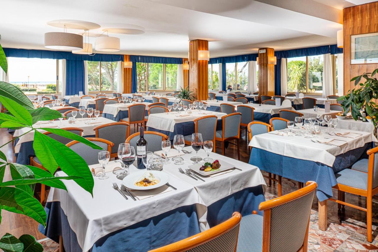een eetkamer met tafels en stoelen en ramen bij Hotel Palace in Bibione +39 foto's