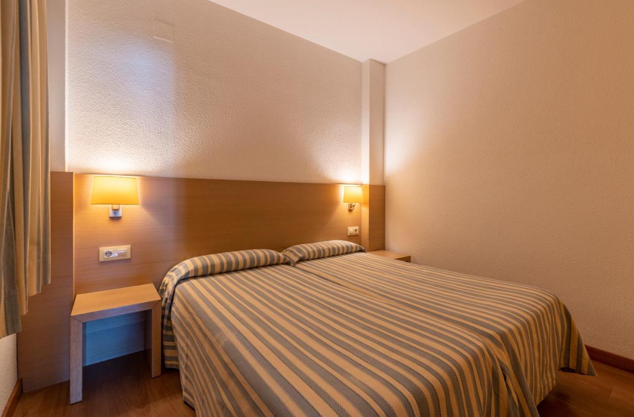 een hotelkamer met een bed, een tafel en lampen bij Almirall Apartaments in Lloret de Mar