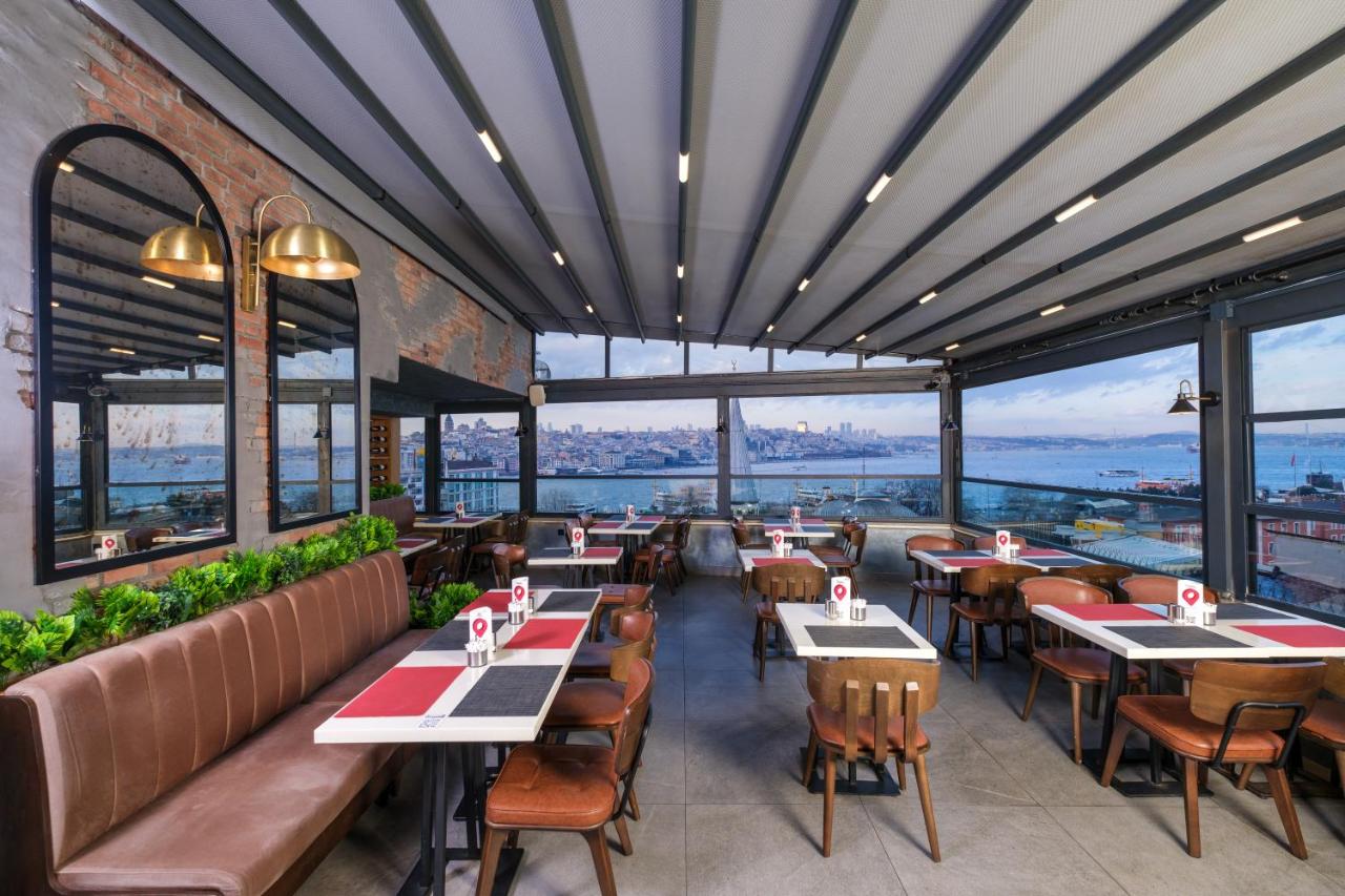 een restaurant met tafels en stoelen en grote ramen bij Glamour Hotel Istanbul Sirkeci in Istanbul