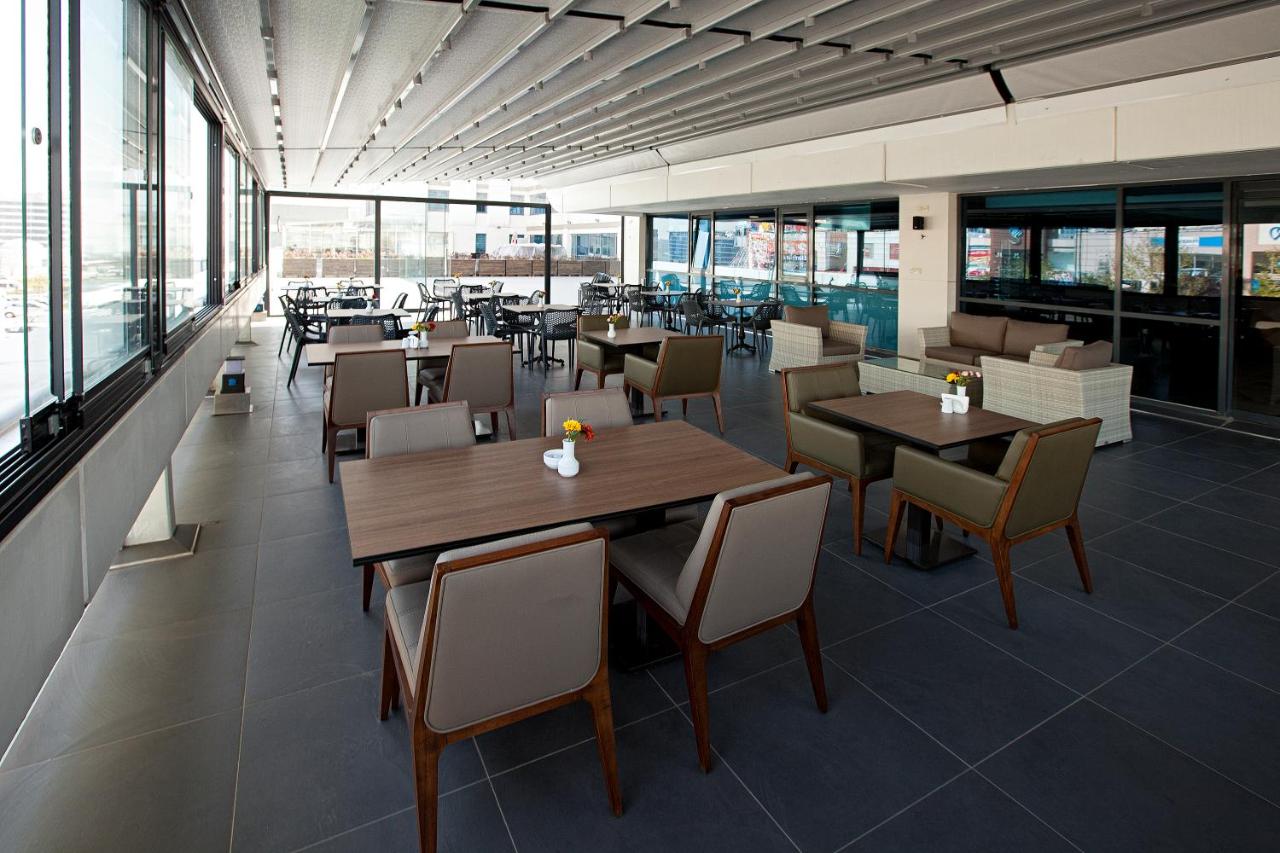 een restaurant met tafels, stoelen en ramen bij Nearport Hotel Sabiha Gokcen Airport in Istanbul