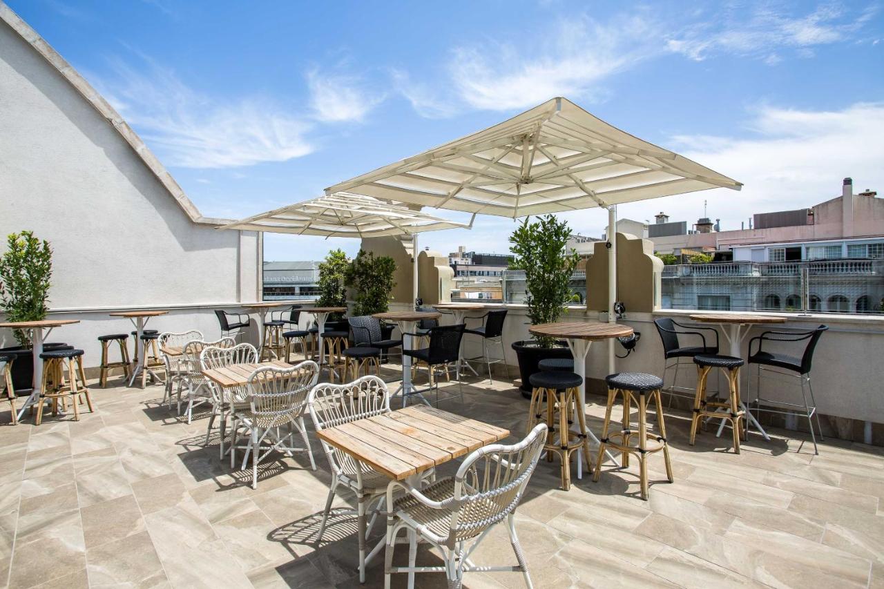 een terras met tafels en stoelen op een dakterras bij Room Mate Anna, Barcelona in Barcelona