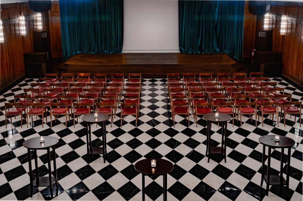 een lege aula met rode stoelen op een geblokte vloer bij Soho House Istanbul in Istanbul