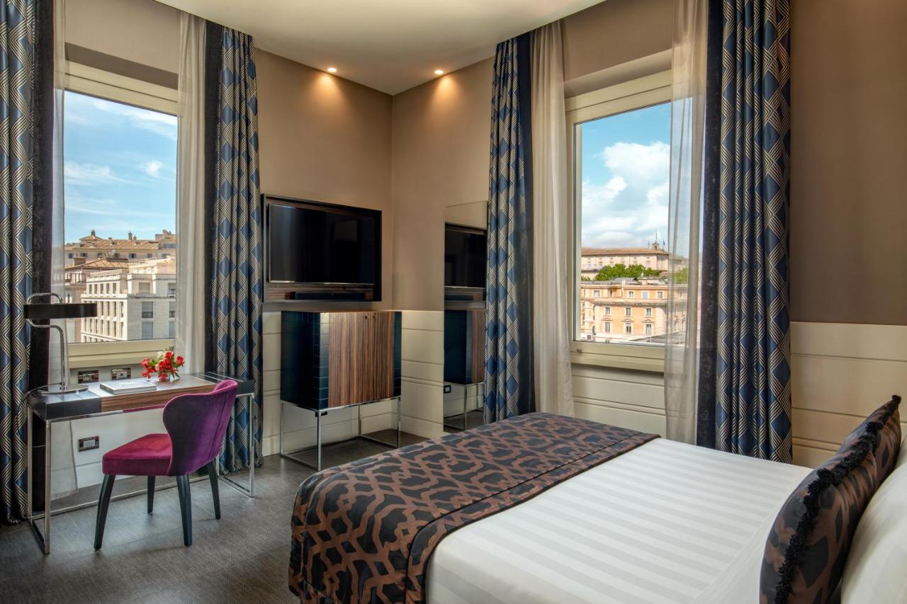 een hotelkamer met een bed, een bureau en twee ramen bij The Glam in Rome