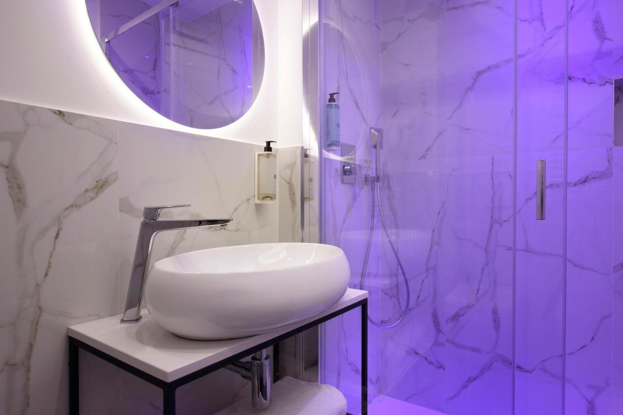 een badkamer met een witte wastafel en een spiegel bij Hotel Patria in Rome +54 foto's