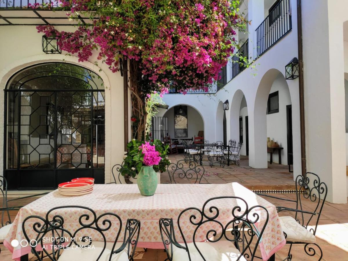 Een tafel en stoelen met roze bloemen op een terras. bij Lince Casa Rural in El Rocío