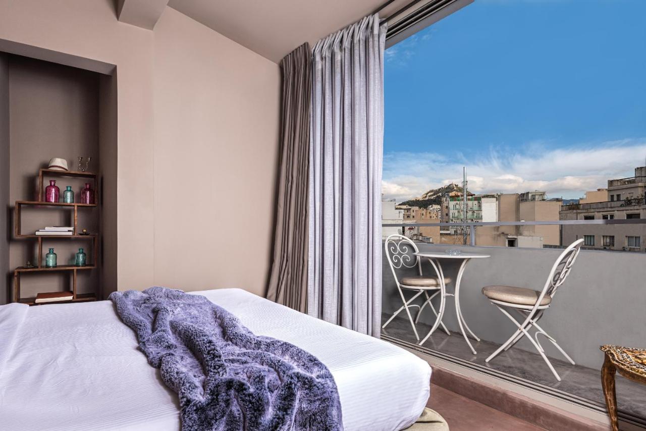 een slaapkamer met een bed en een balkon met een tafel bij iFeel Athens Suites in Athene