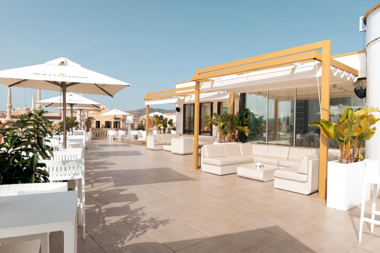 een terras bij een hotel met witte stoelen en parasols bij Hotel Casa Fuster G.L Monumento in Barcelona