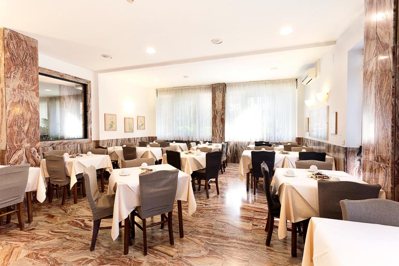 een eetkamer met witte tafels en stoelen bij Hotel Corolle in Florence