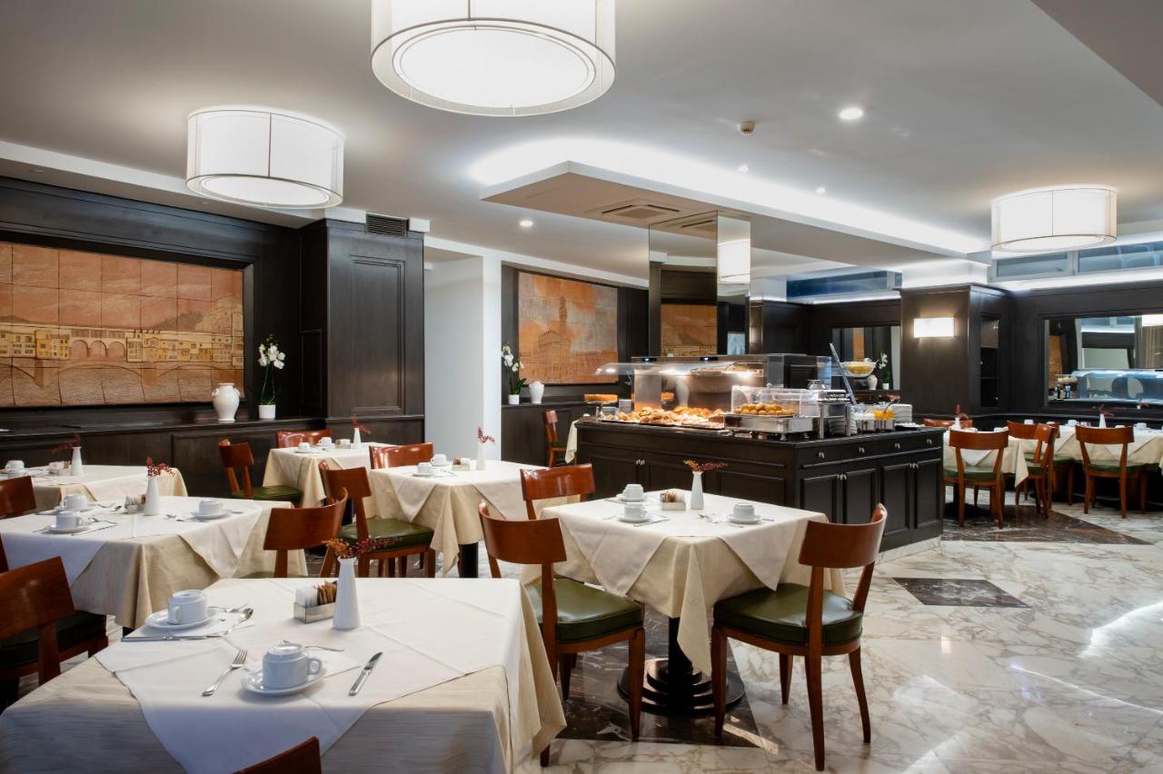 een restaurant met witte tafels en stoelen en een keuken bij Hotel Grifone Firenze - Meetings & Spa in Florence