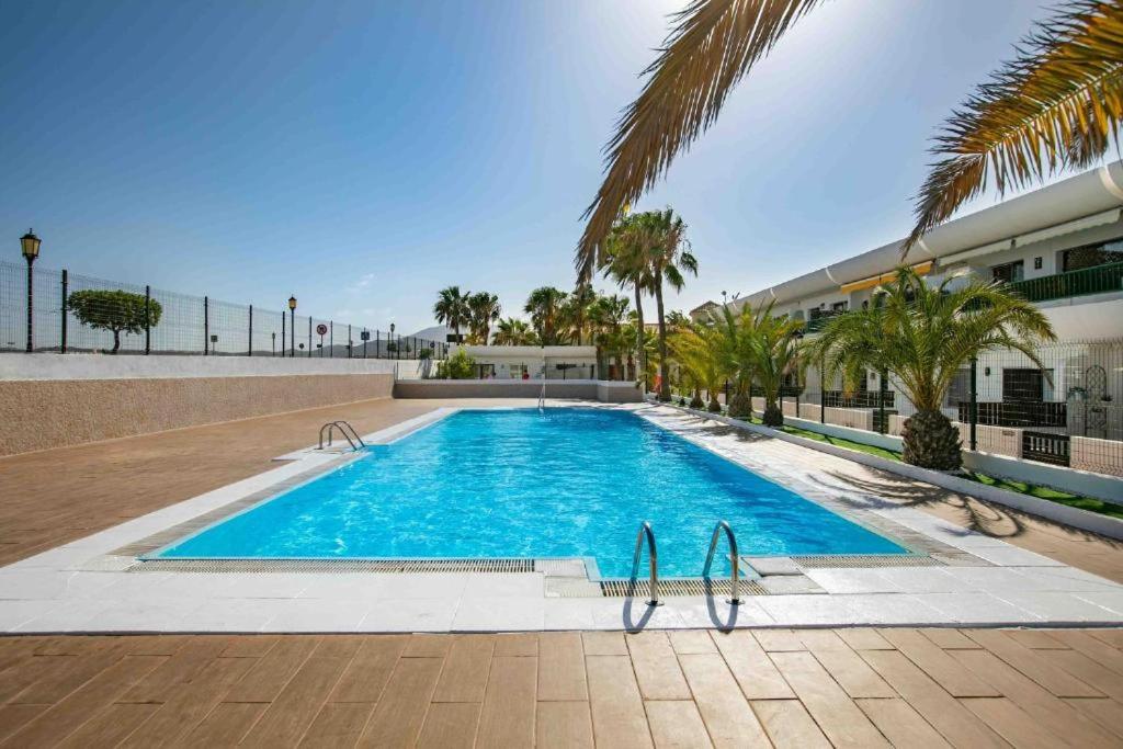 een zwembad met palmbomen en een gebouw bij Dunasol 311 in Corralejo