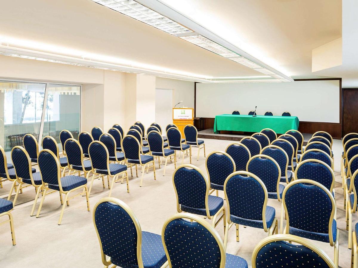 een lege kamer met stoelen en een projectiescherm bij President Hotel Palermo in Palermo