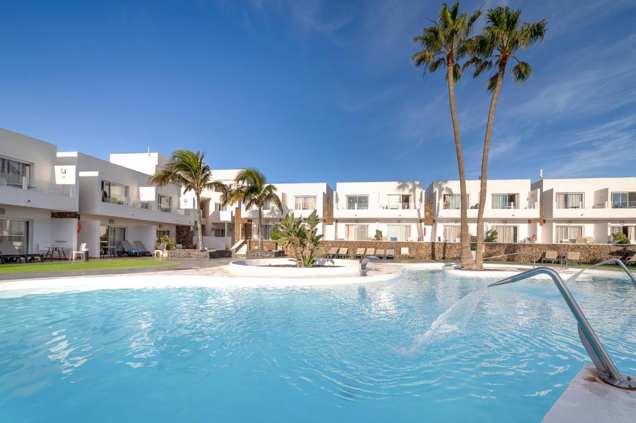 een zwembad met palmbomen voor een gebouw bij Hotel Siroco by SeaSense- Adults Only 18 in Costa Teguise +42 foto's