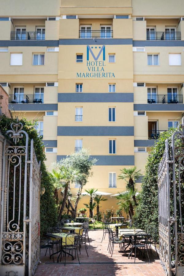 een hotel met tafels en stoelen voor een gebouw bij Hotel Villa Margherita in Ladispoli
