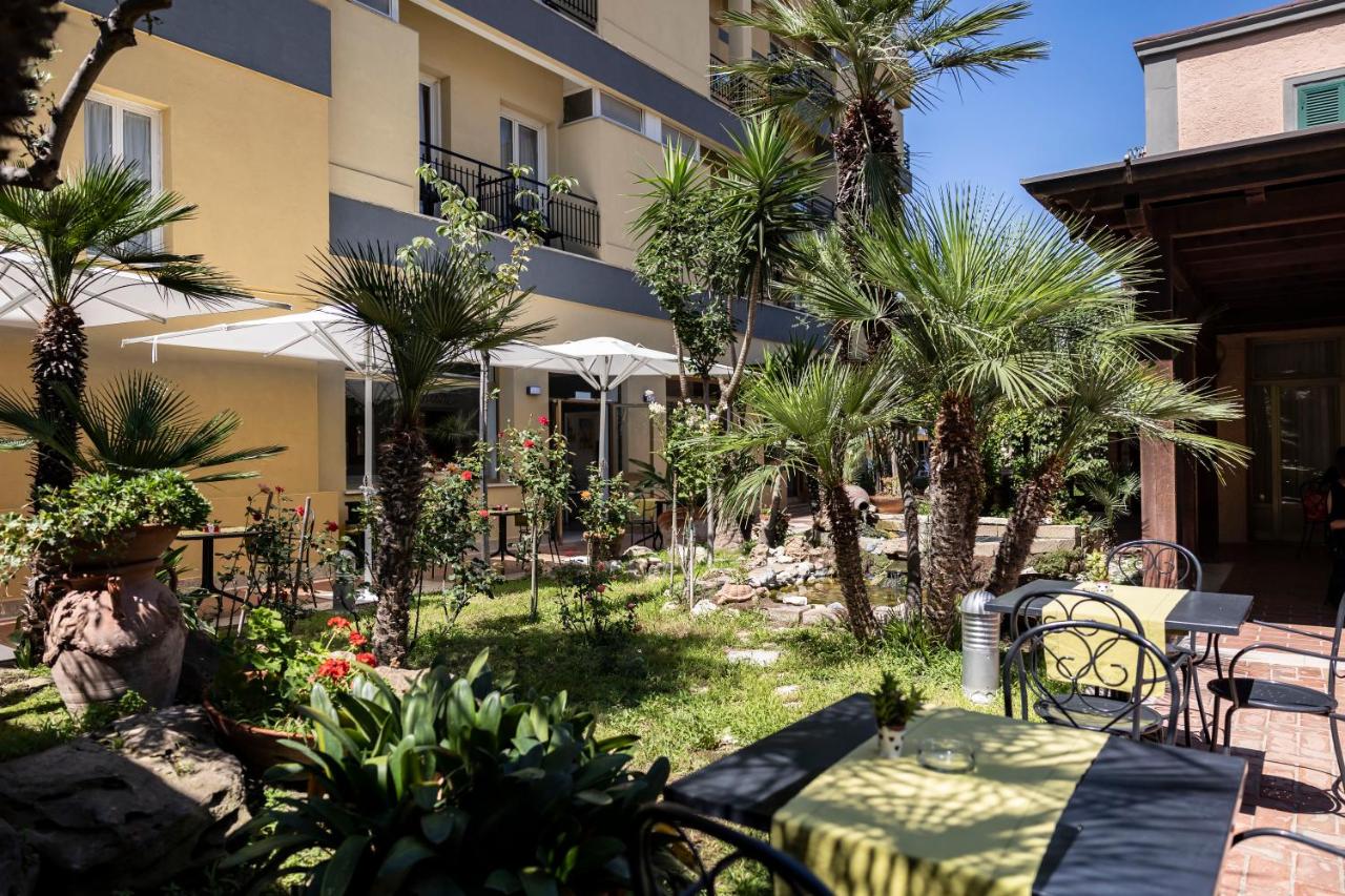 een terras met een tafel en stoelen voor een gebouw bij Hotel Villa Margherita in Ladispoli