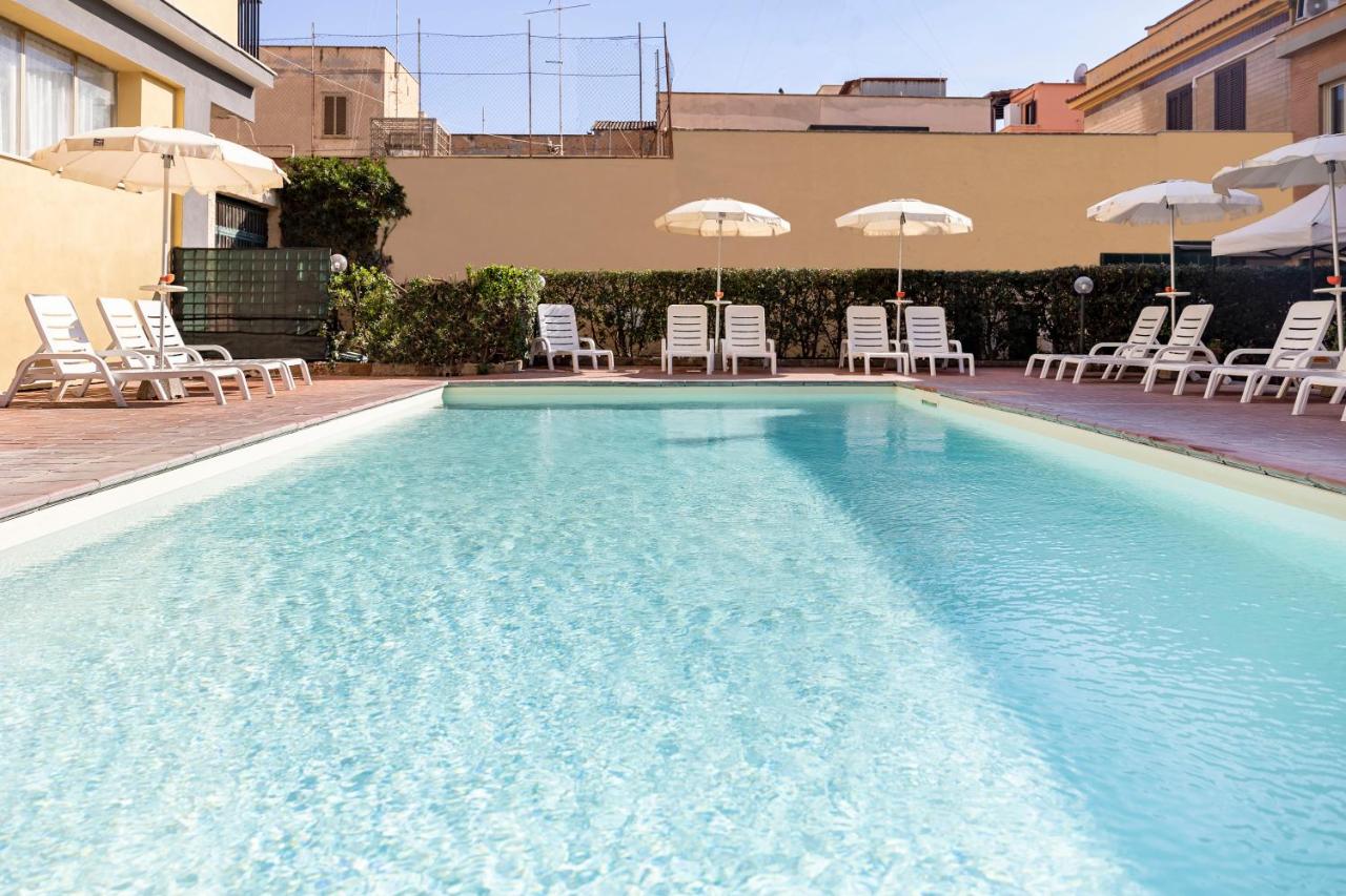 een groot zwembad met ligstoelen en parasols bij Hotel Villa Margherita in Ladispoli