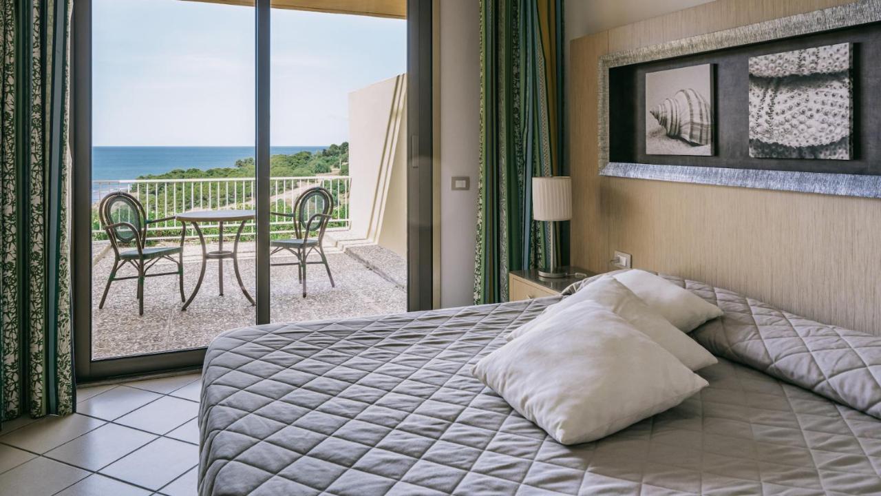een slaapkamer met een bed en een balkon met een tafel bij MClub Cala Regina in Sciacca