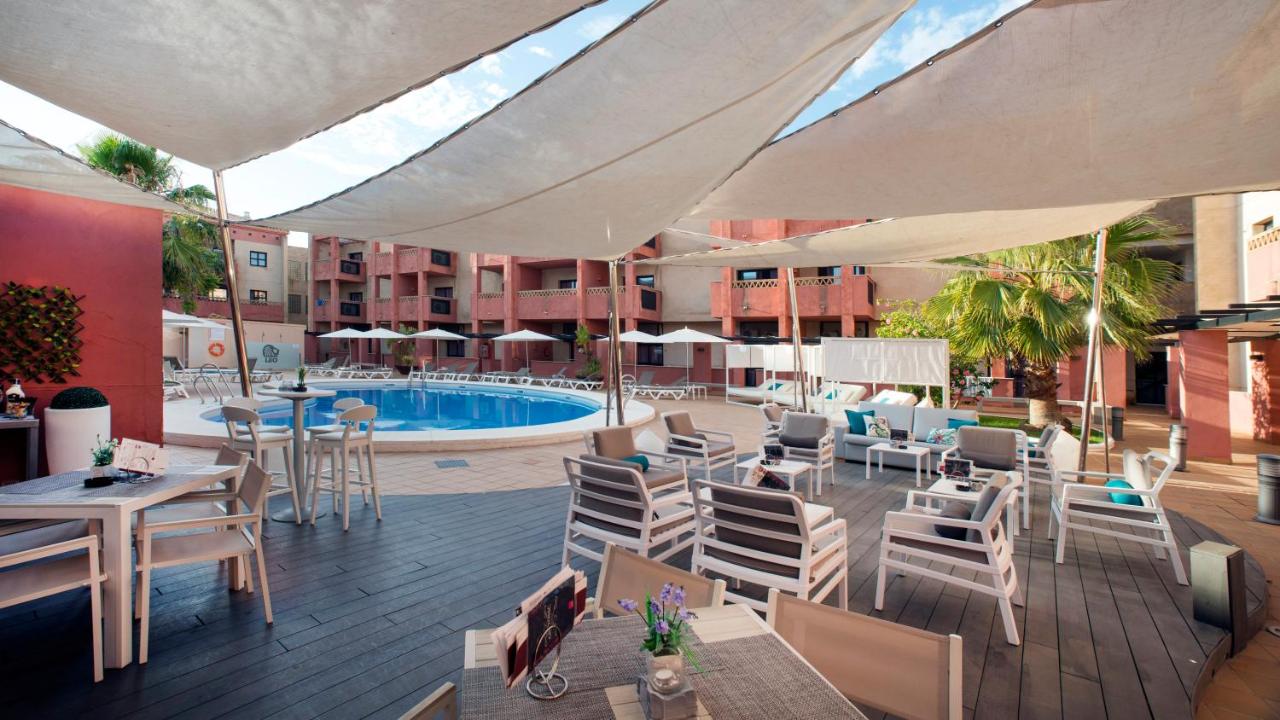 een buitenterras met tafels en stoelen en een zwembad bij Leo Punta Umbría - Adults Only in Punta Umbría